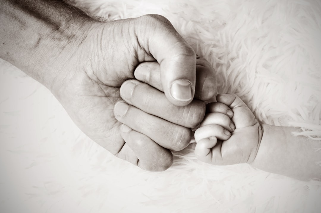 An adult fist and infant fist touching implying the strength of all community members.